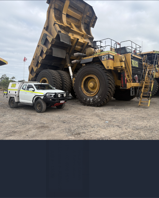 Massive mining haul truck beside a white pickup on a gravel lot, with a person on the truck ladder — Resurge Diesel & Fabrication Pty Ltd In Balnagowan, QLD