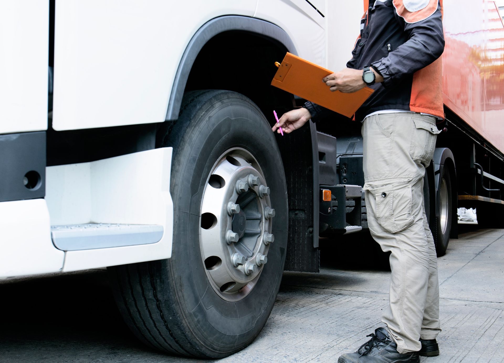 Person In Work Attire Inspecting Truck Tyre With Clipboard — Resurge Diesel & Fabrication Pty Ltd In Balnagowan, QLD