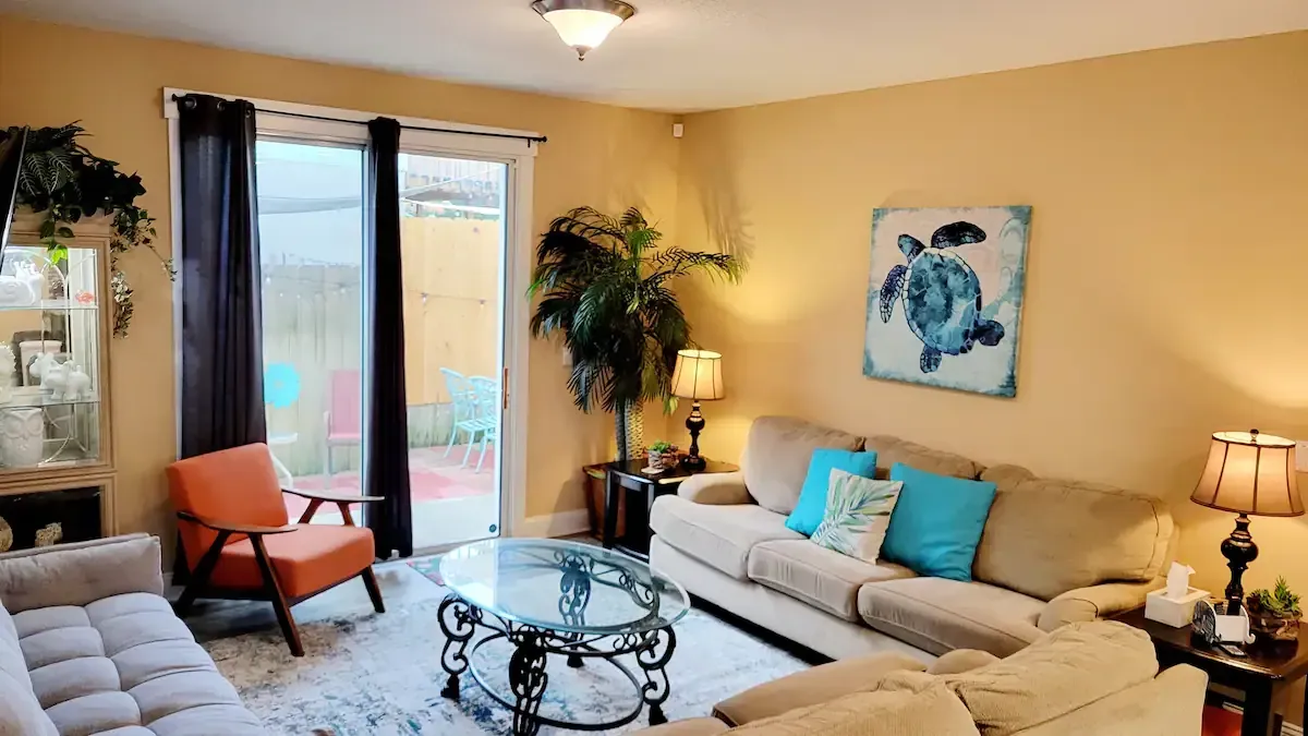 A living room with a couch , chair , coffee table and a painting on the wall.