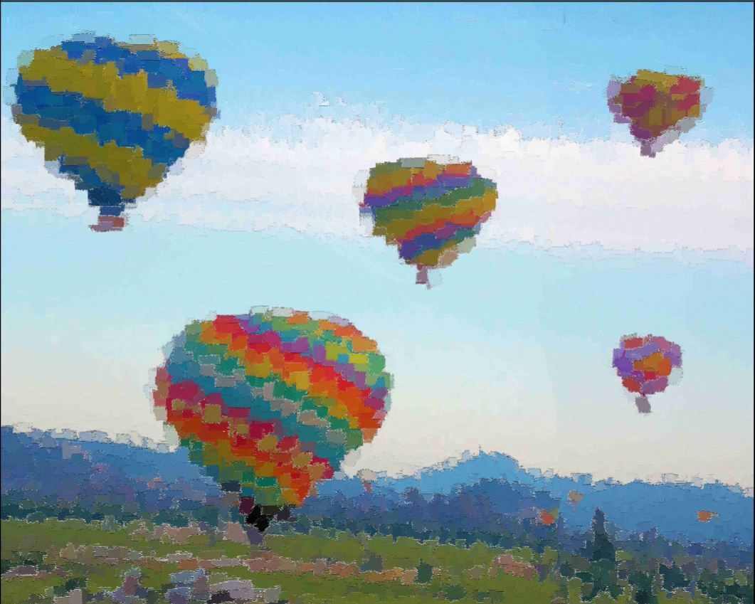 Colorful hot air balloons floating over a grassy field with mountains in the distance.