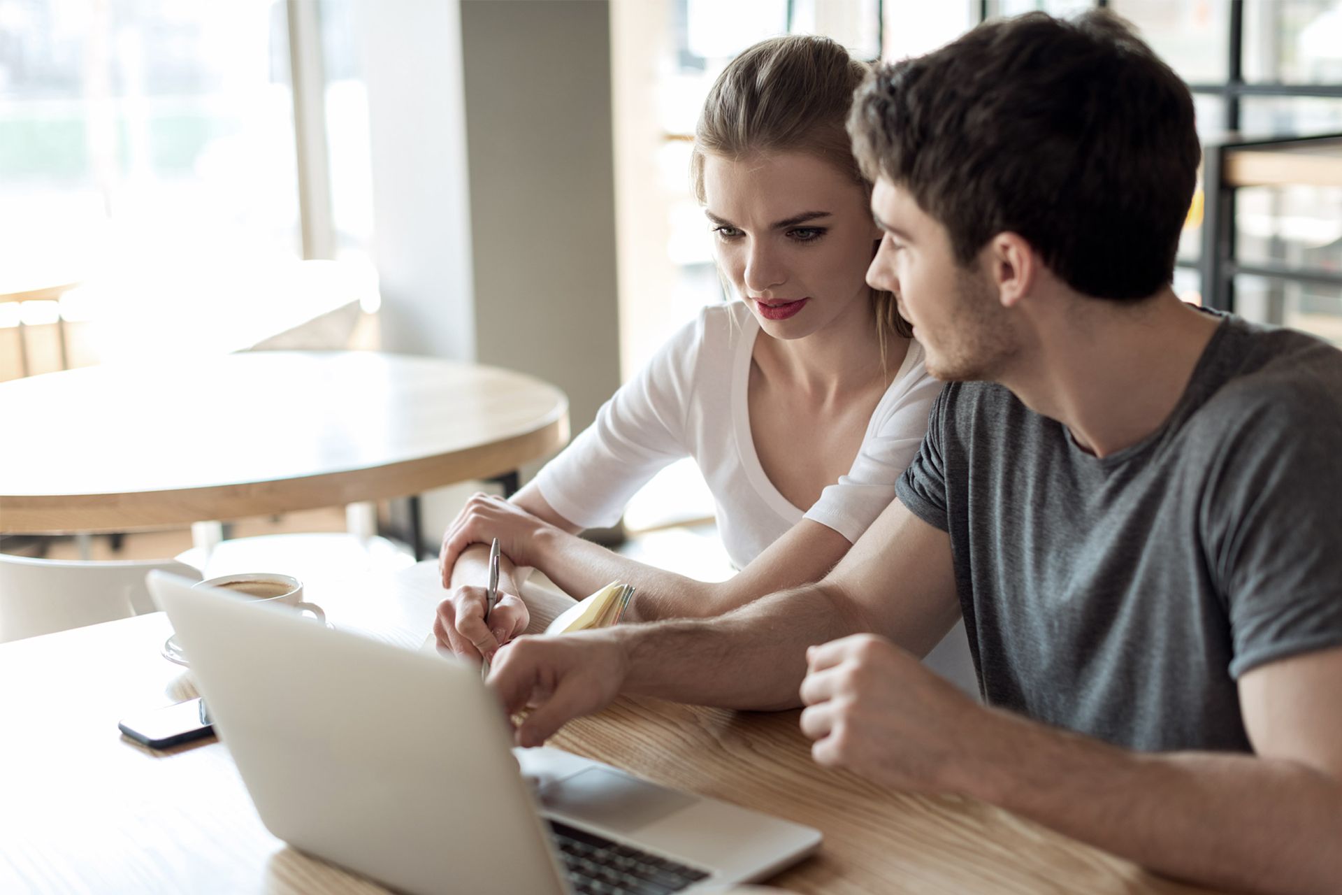 Ein Mann und eine Frau sitzen an einem Tisch und schauen auf einen Laptop.