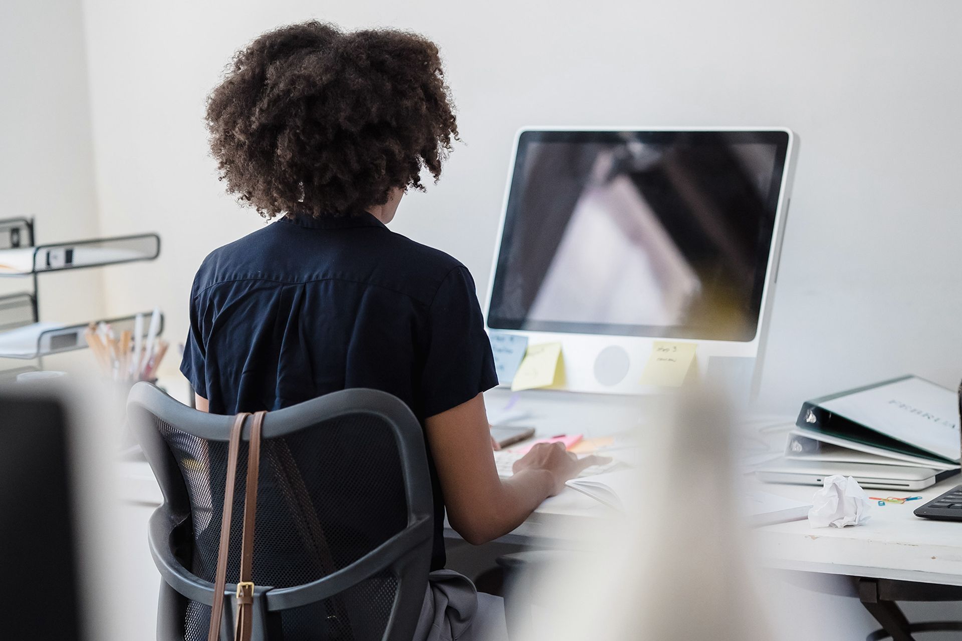 Eine Frau sitzt an einem Schreibtisch vor einem Computer.