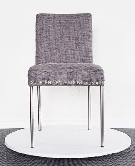 Een grijze, gestoffeerde eetkamerstoel met slanke, zilverkleurige metalen poten, die op een rond wit platform staat.