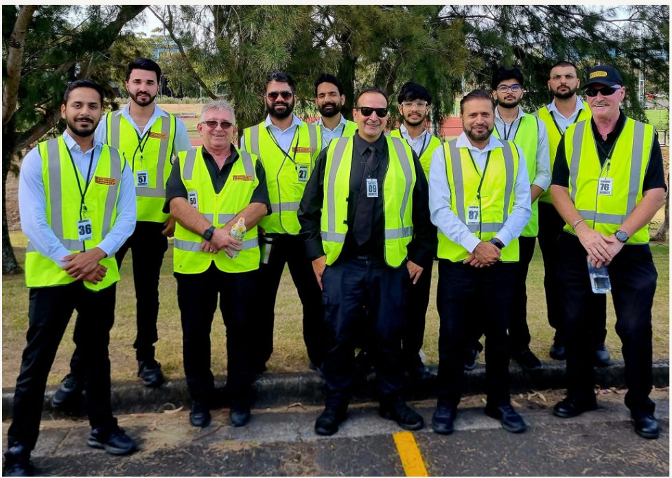 Group of people wearing yellow vests posing outdoors.