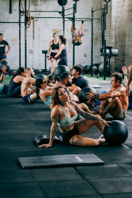 Group fitness class on gym mats, with people stretching and exercising in a warehouse-style studio