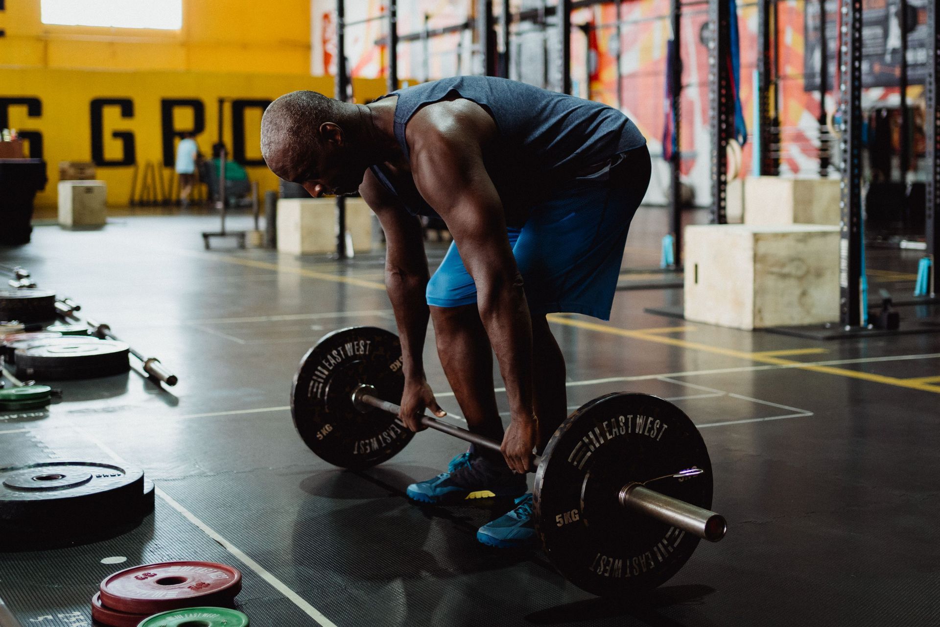 Person bent over loading a barbell in a gym with colorful graffiti walls