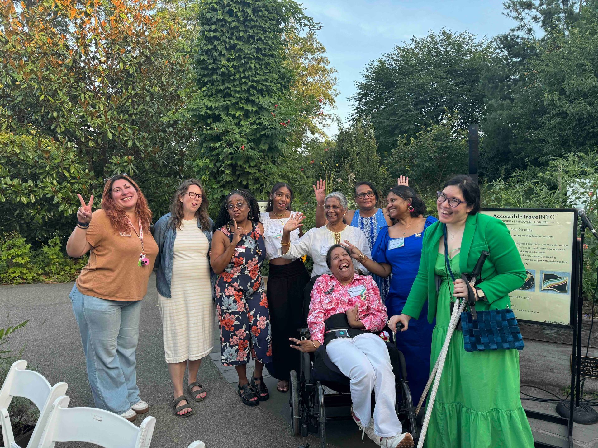 Nine workshop participants, BBG staff members, and family members posing with playful expressions amid the greenery at Brooklyn Botanic Garden.