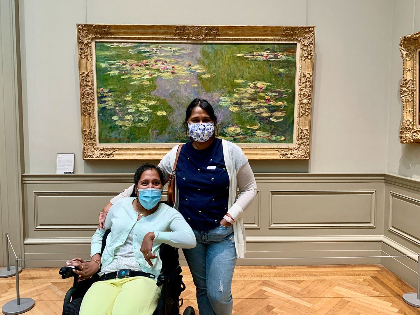 Annie and I smiling behind our masks.  A large  Monet Water Lilies painting is behind us framed in an elaborate gold framing.