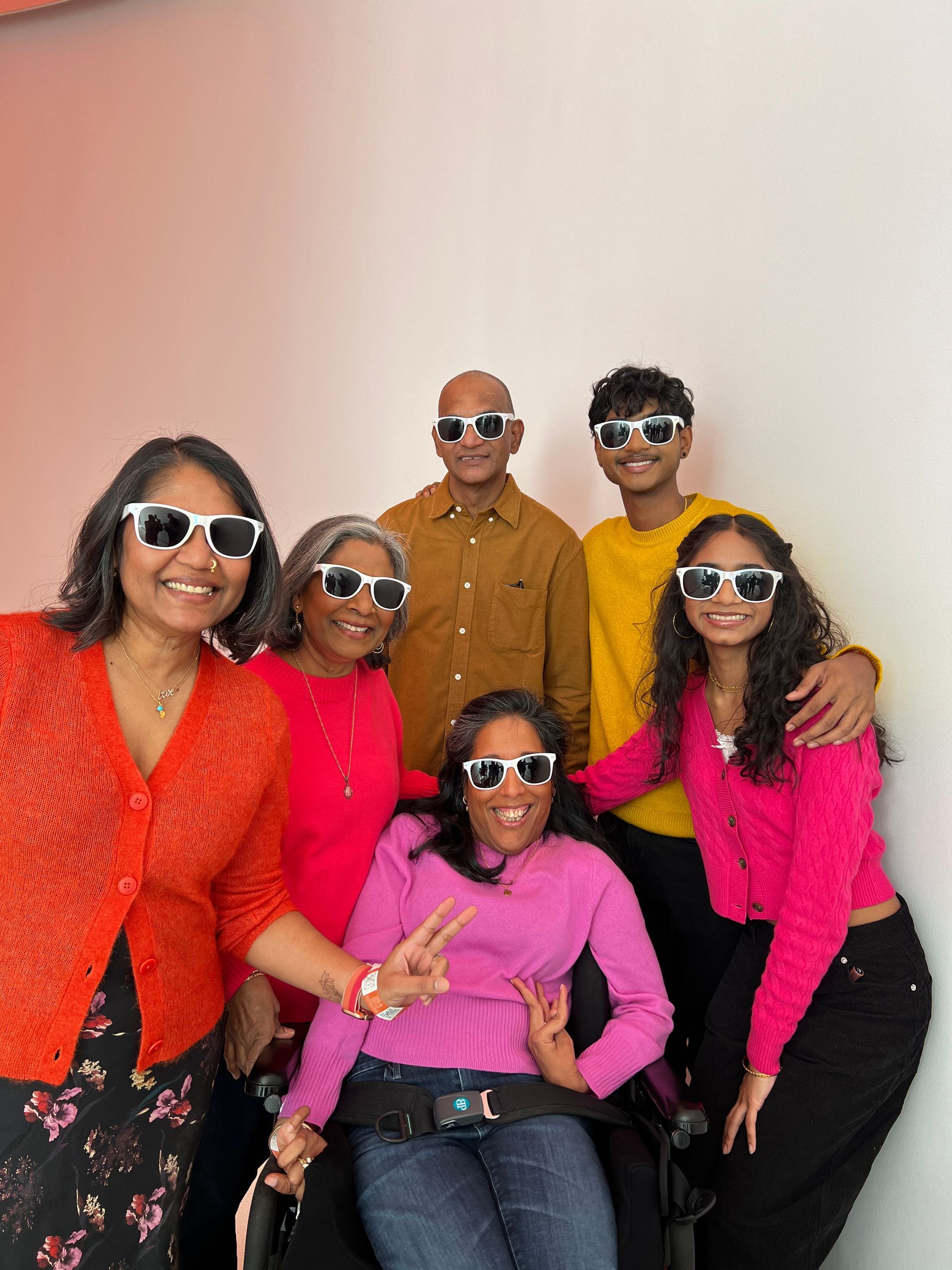 A family photo with everyone wearing sunshades smiling and posing for the camera. 