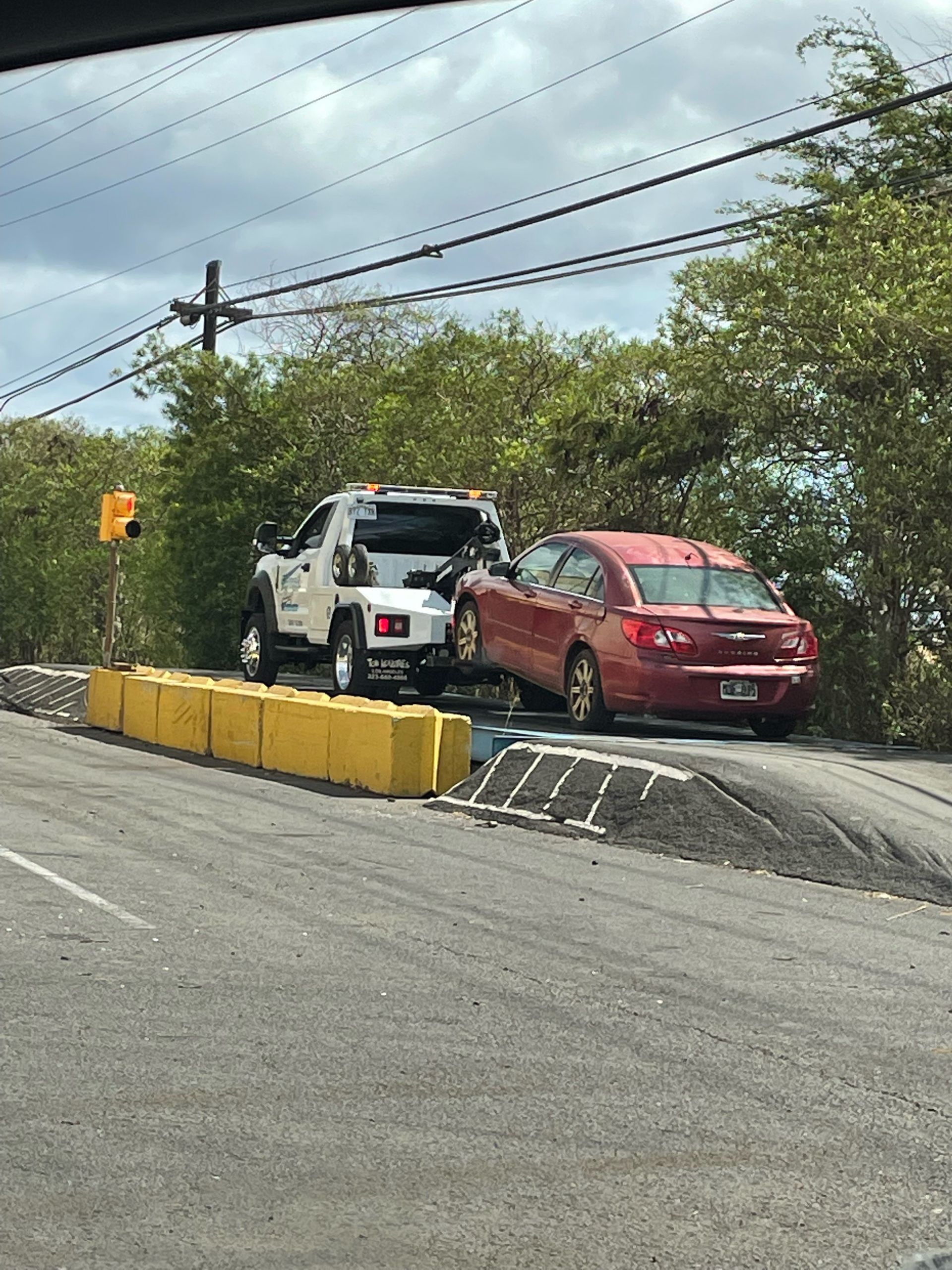White car being towed on a flatbed tow truck. The truck is white with orange safety lights.
