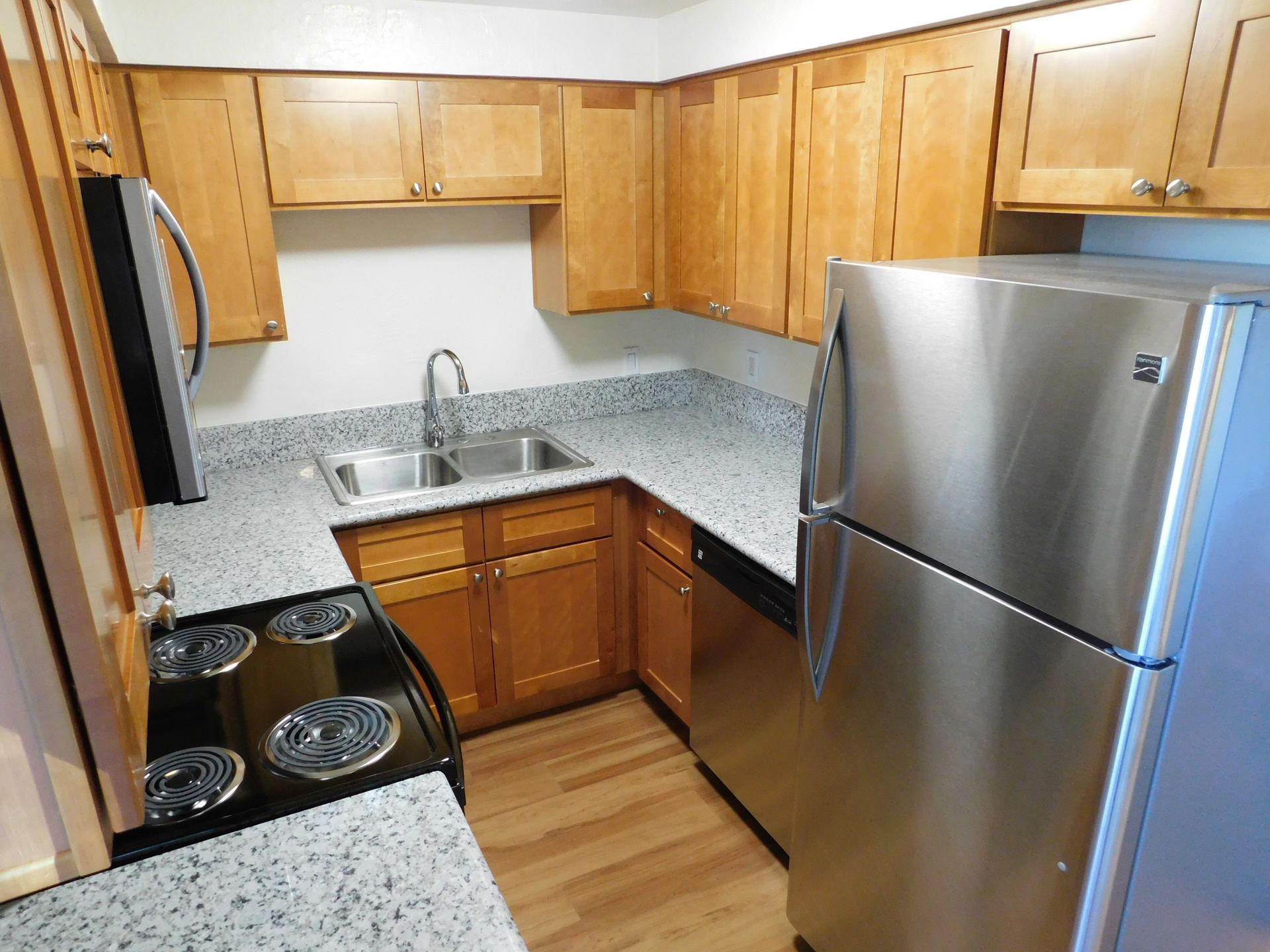 Kitchen with light brown cabinets, stainless steel appliances, and gray countertops.