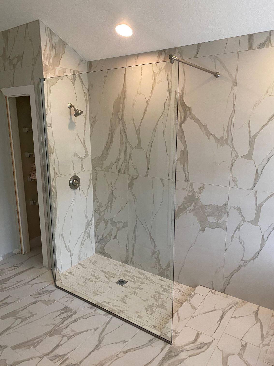 A bathroom with marble walls and a walk in shower.