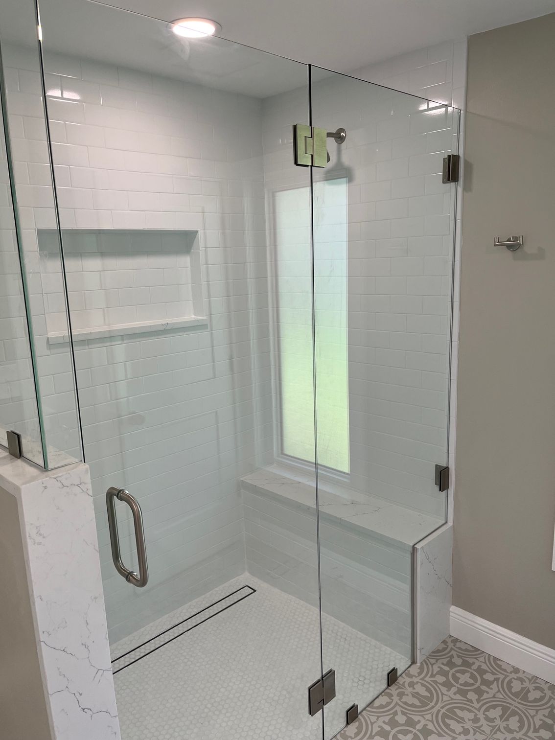 A bathroom with a glass shower door and a window.