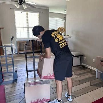 Man packing boxes in a room, with a hand truck.