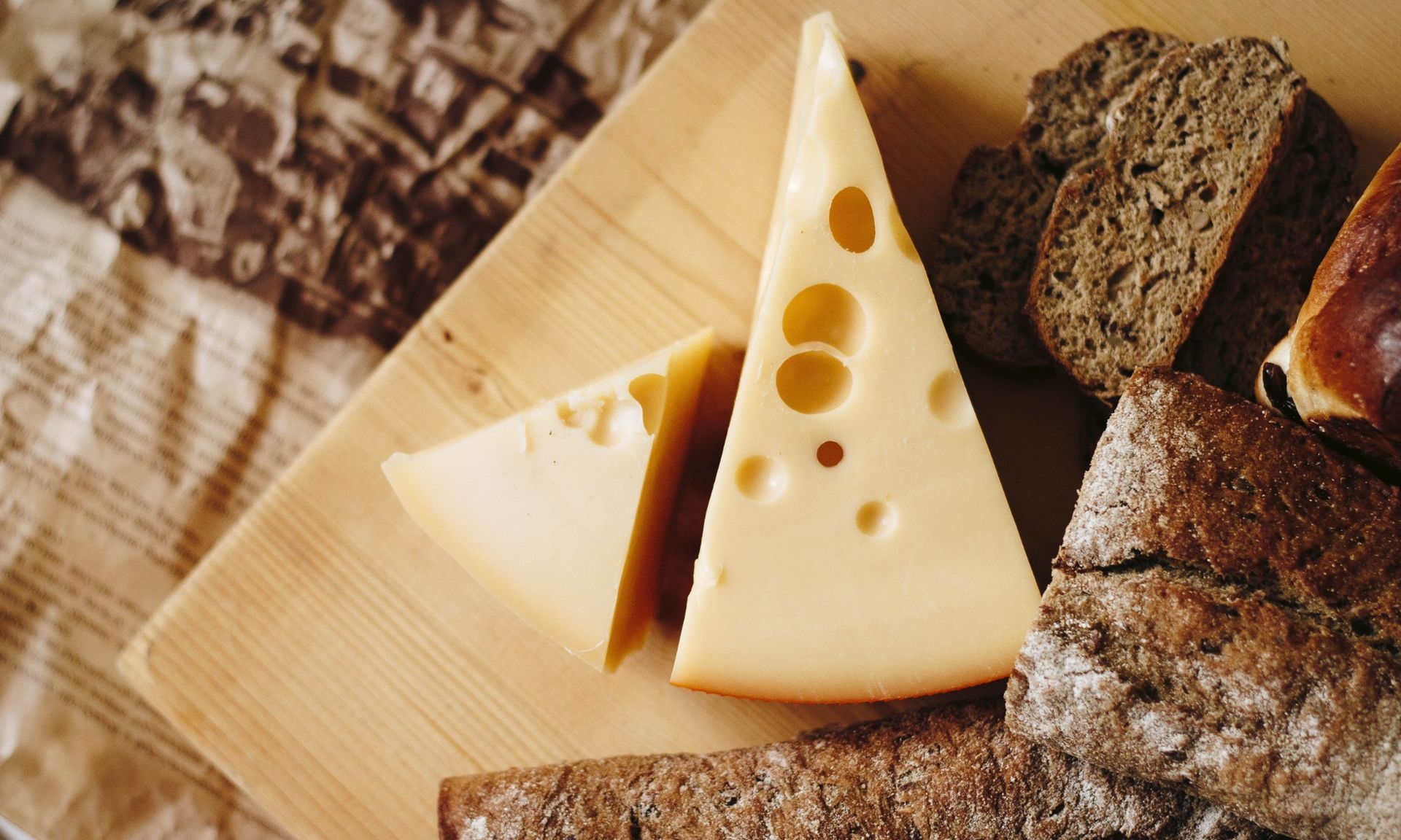 Een houten snijplank belegd met plakjes kaas en brood.