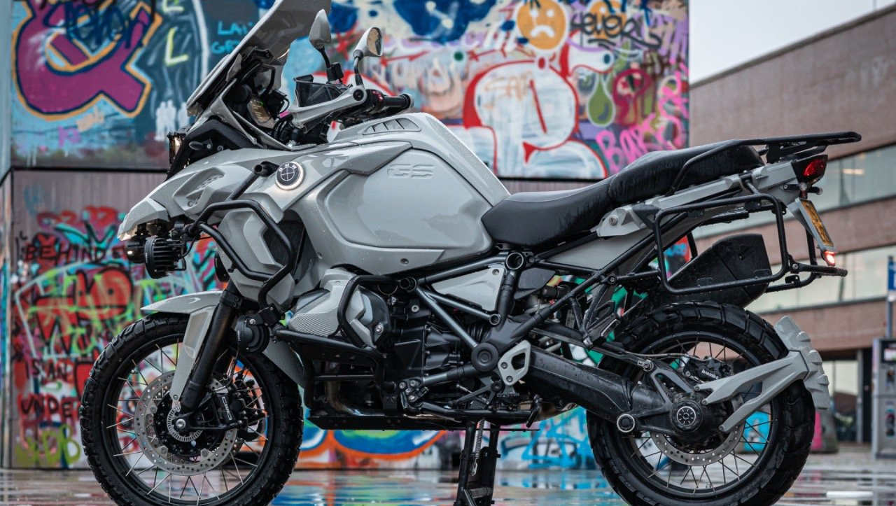 Een motorfiets staat geparkeerd voor een met graffiti bedekte muur.