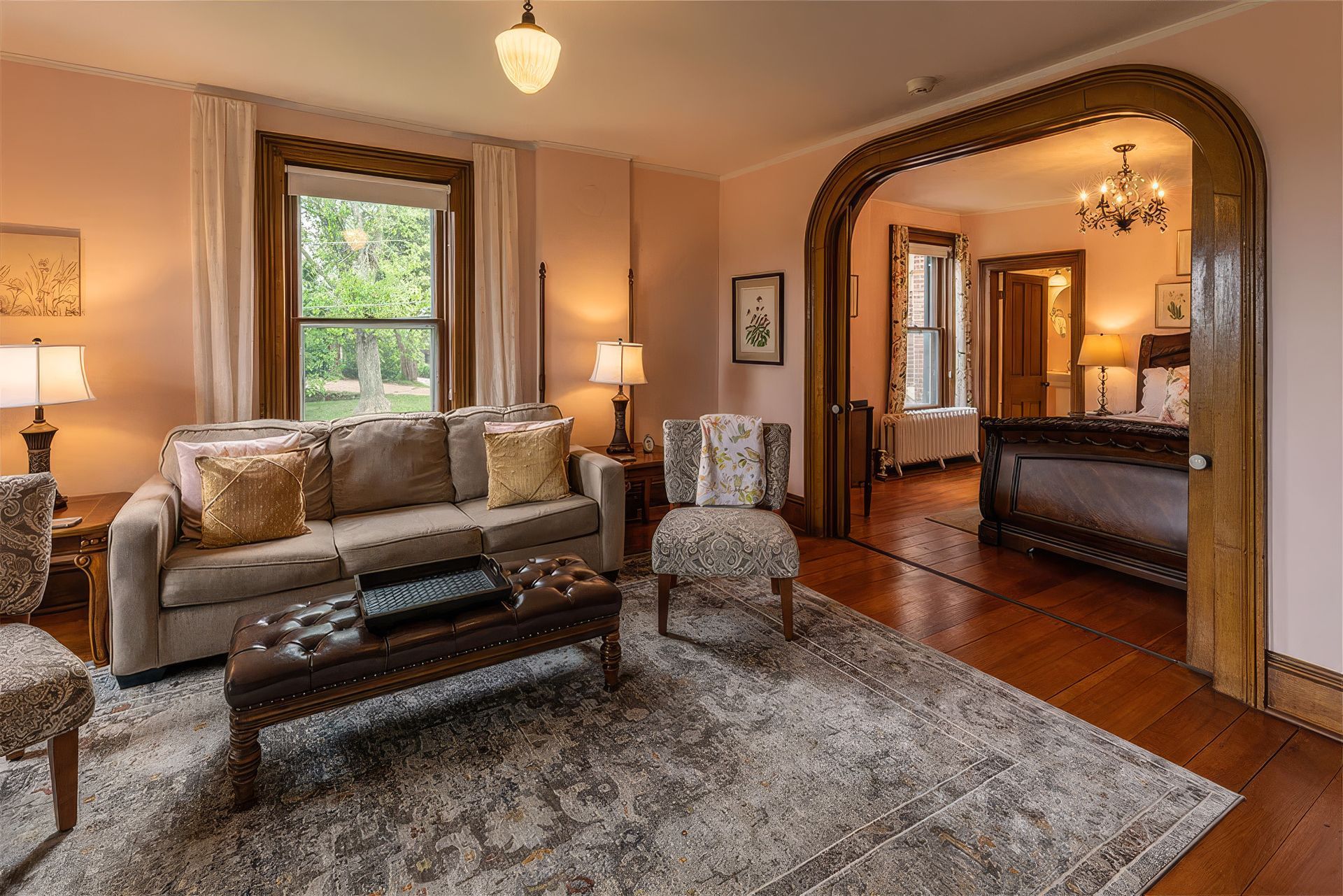 Cozy living room with sofa, patterned rug, window, and arched doorway to a dining area