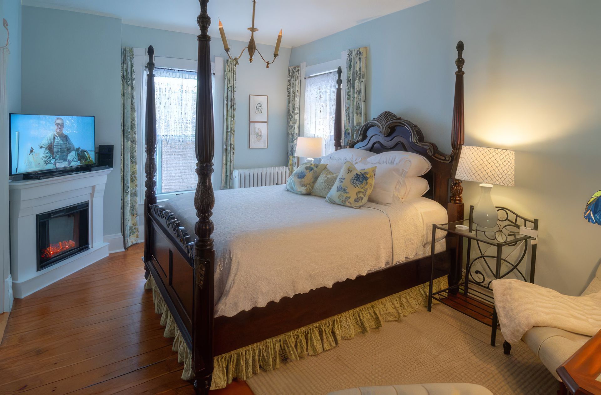 Elegant bedroom with four-poster bed, fireplace, and soft blue walls