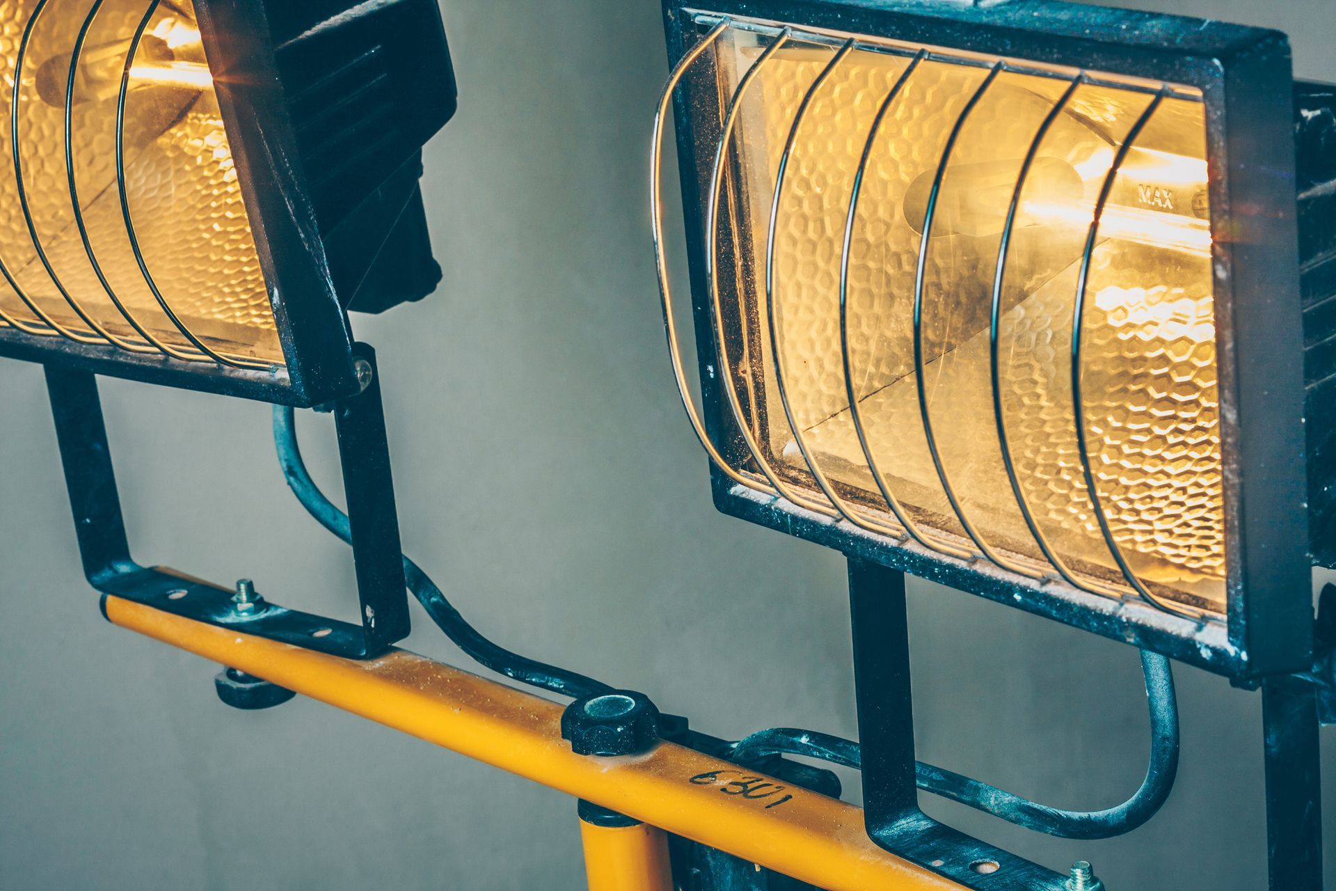 Two lights are sitting on top of a yellow pole.