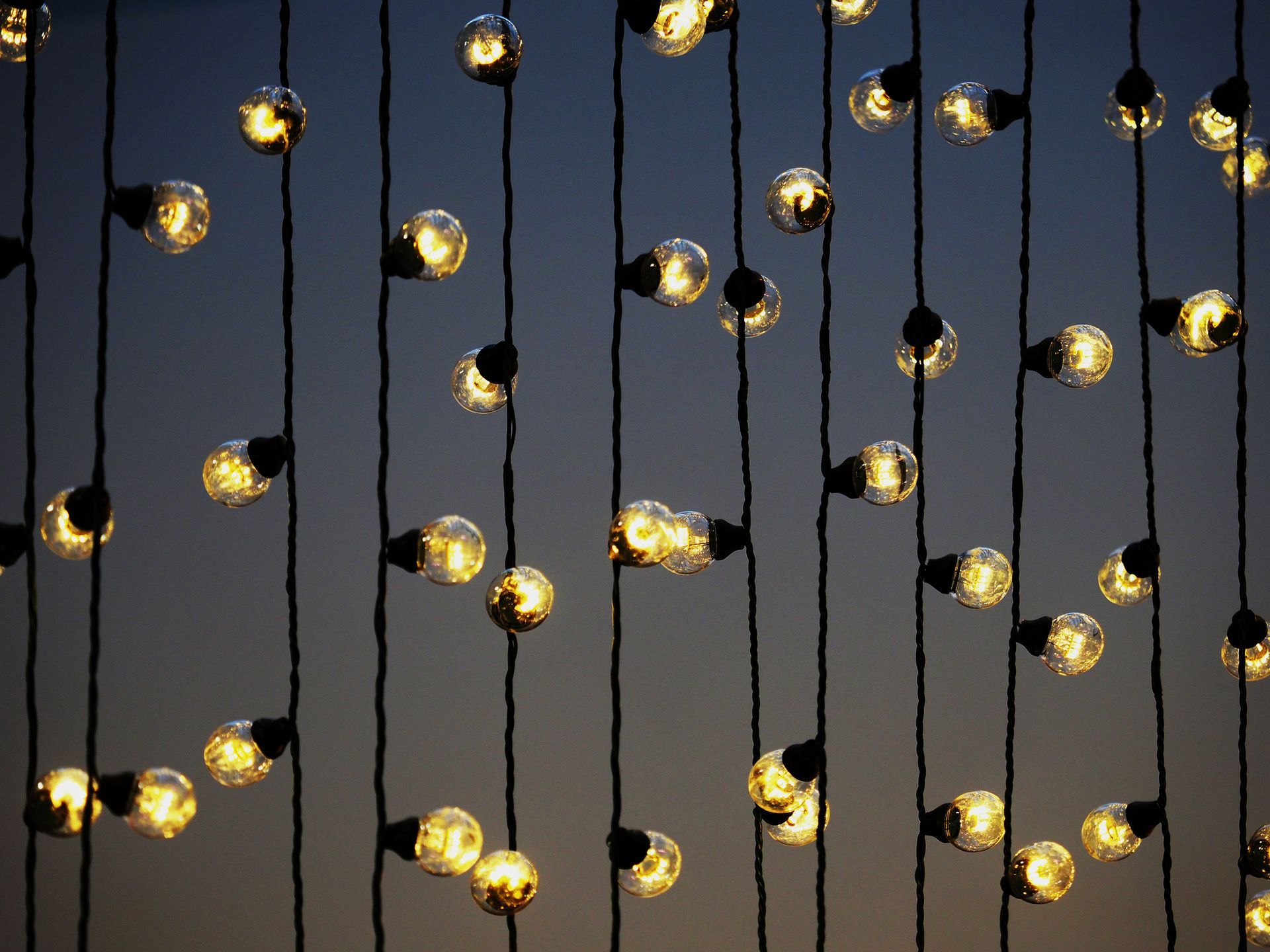 A bunch of lights hanging from a string against a blue sky.