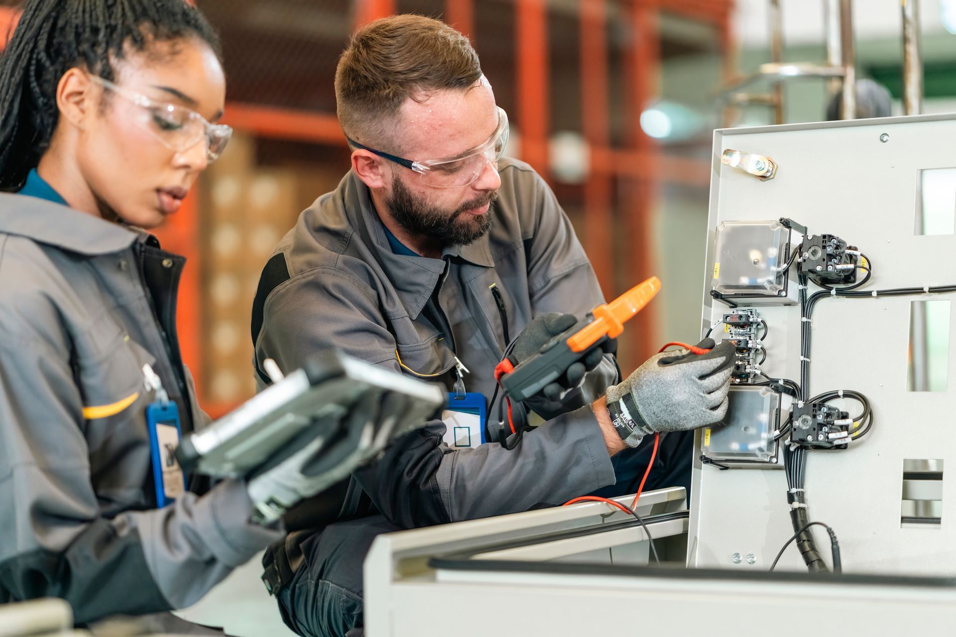 A man and a woman are working on a machine in a factory.