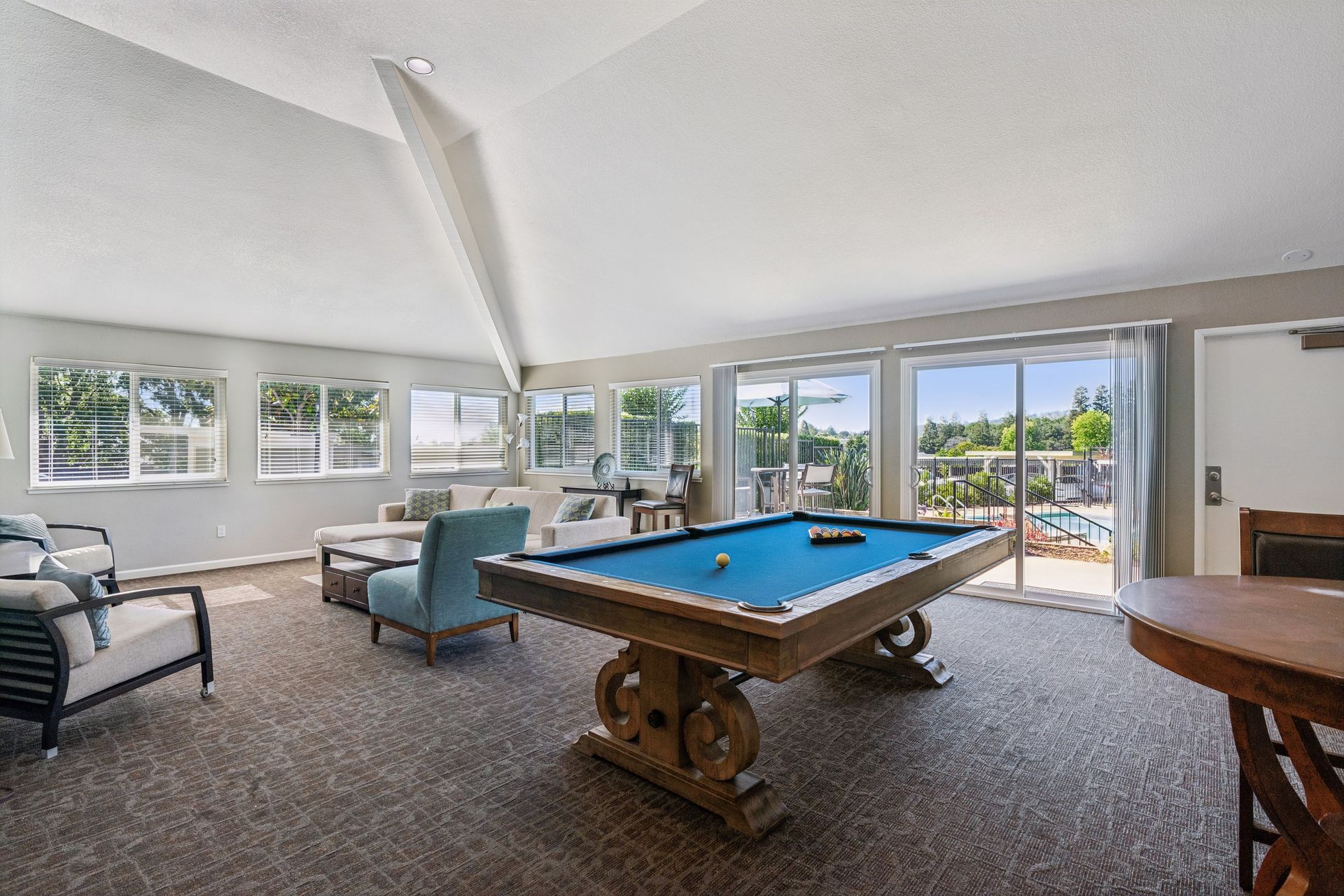 Bright game room with a pool table, seating area, windows, and sliding doors to a sunny patio