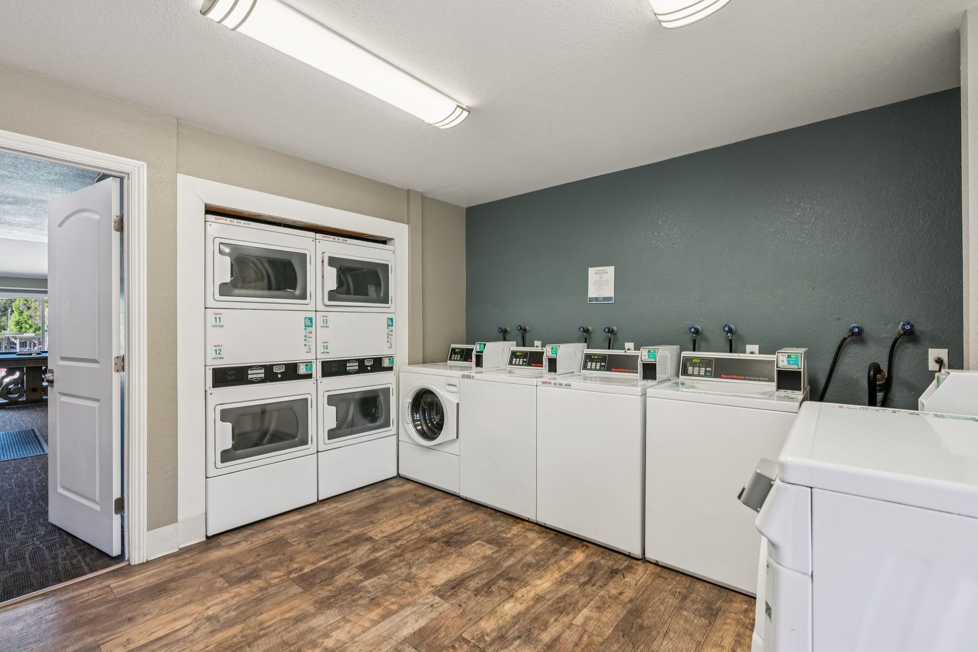 Laundry room with white appliances, cabinets, and a teal accent wall.
