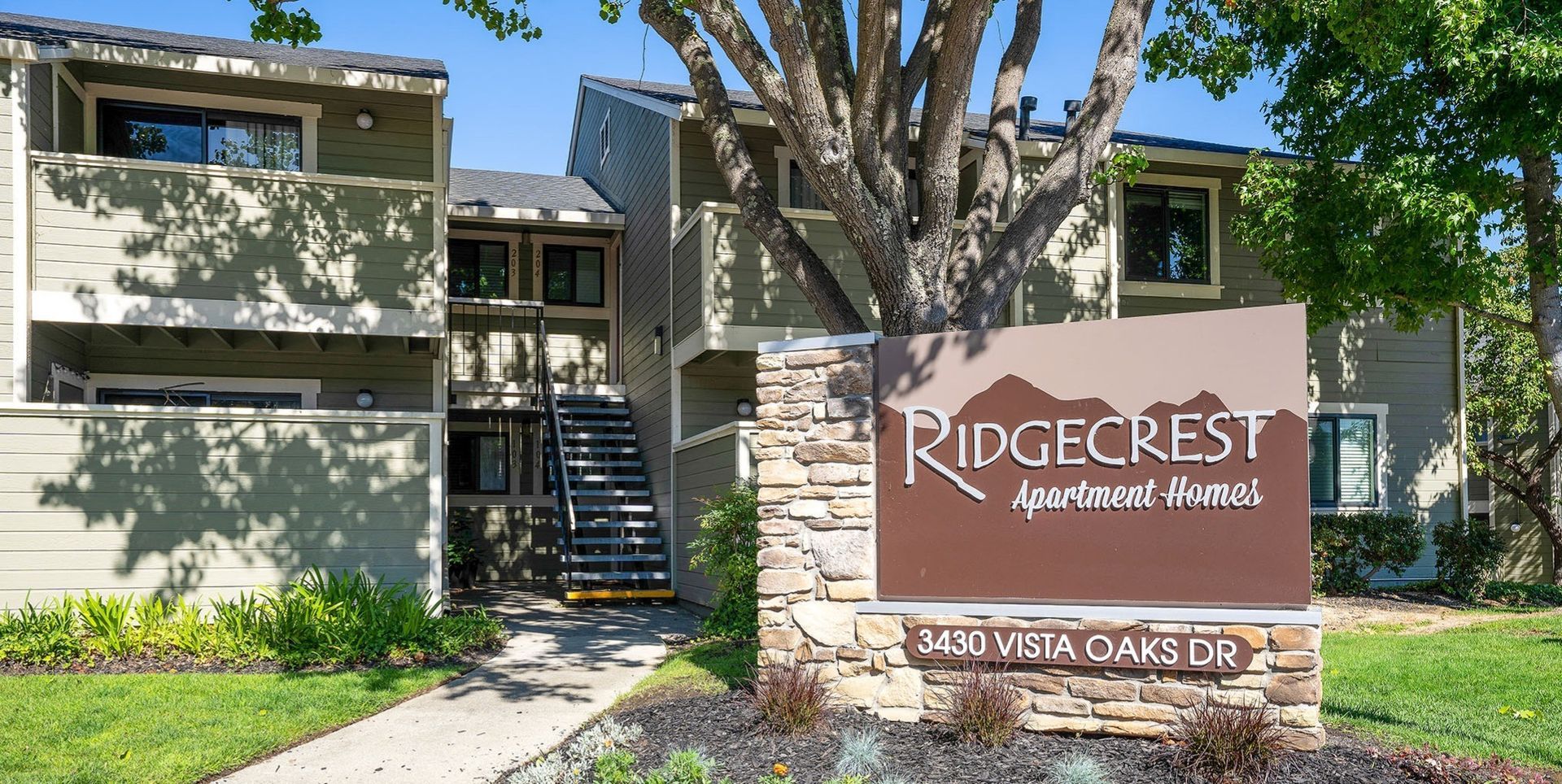 Exterior view of Ridgecrest Apartment Homes entrance with sign and landscaping at Ridgecrest Apartment Homes.