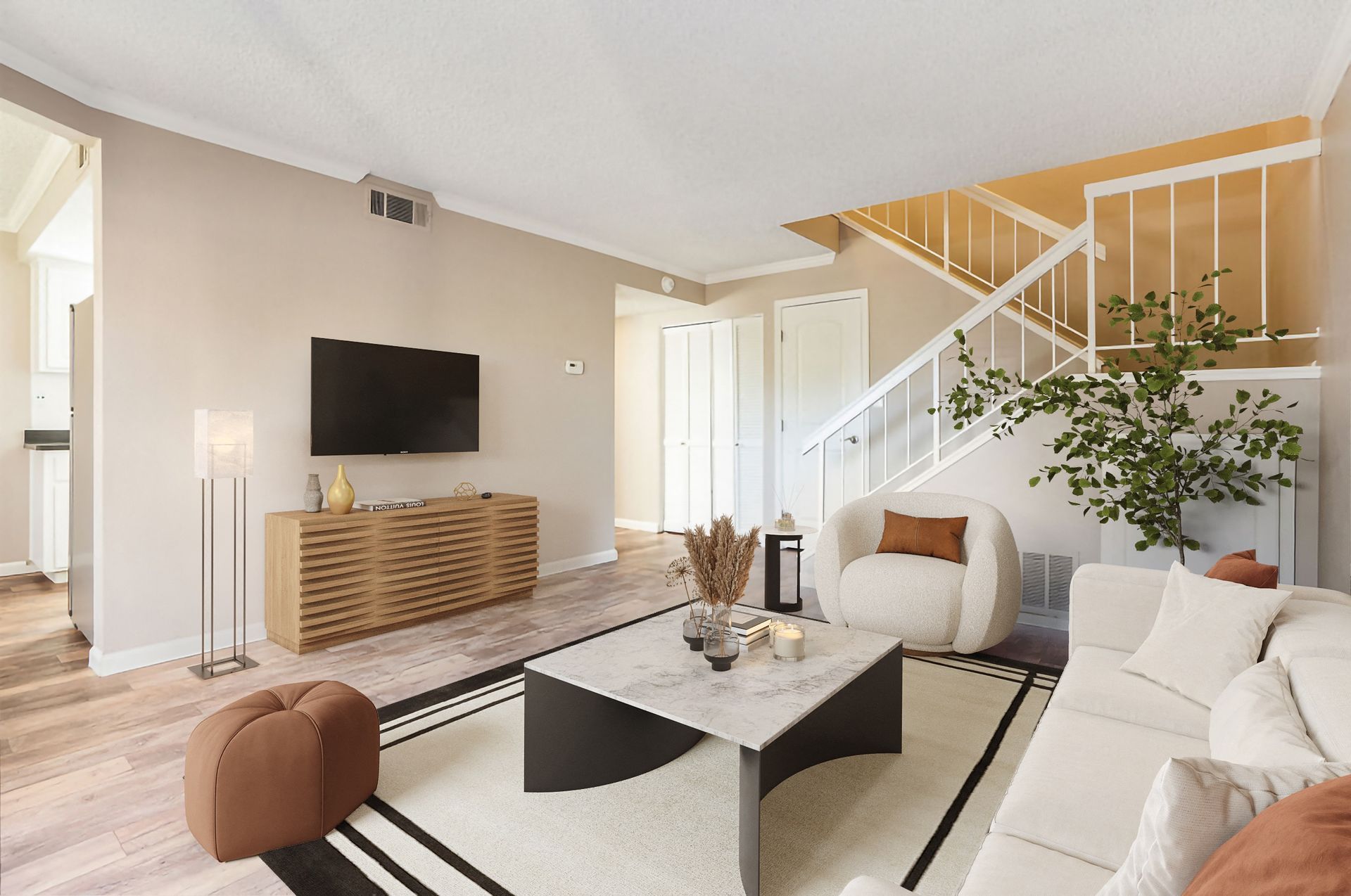 Bright apartment living room with TV, console, sofa, and staircase at Ridgecrest Apartment Homes.