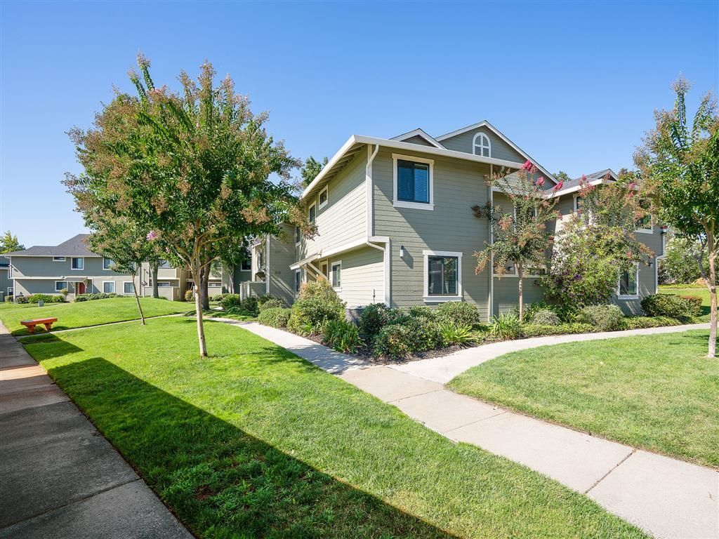 Exterior view of a multi-building apartment community with green lawns, trees, and curved walkways at Ridgecrest Apartment Homes.