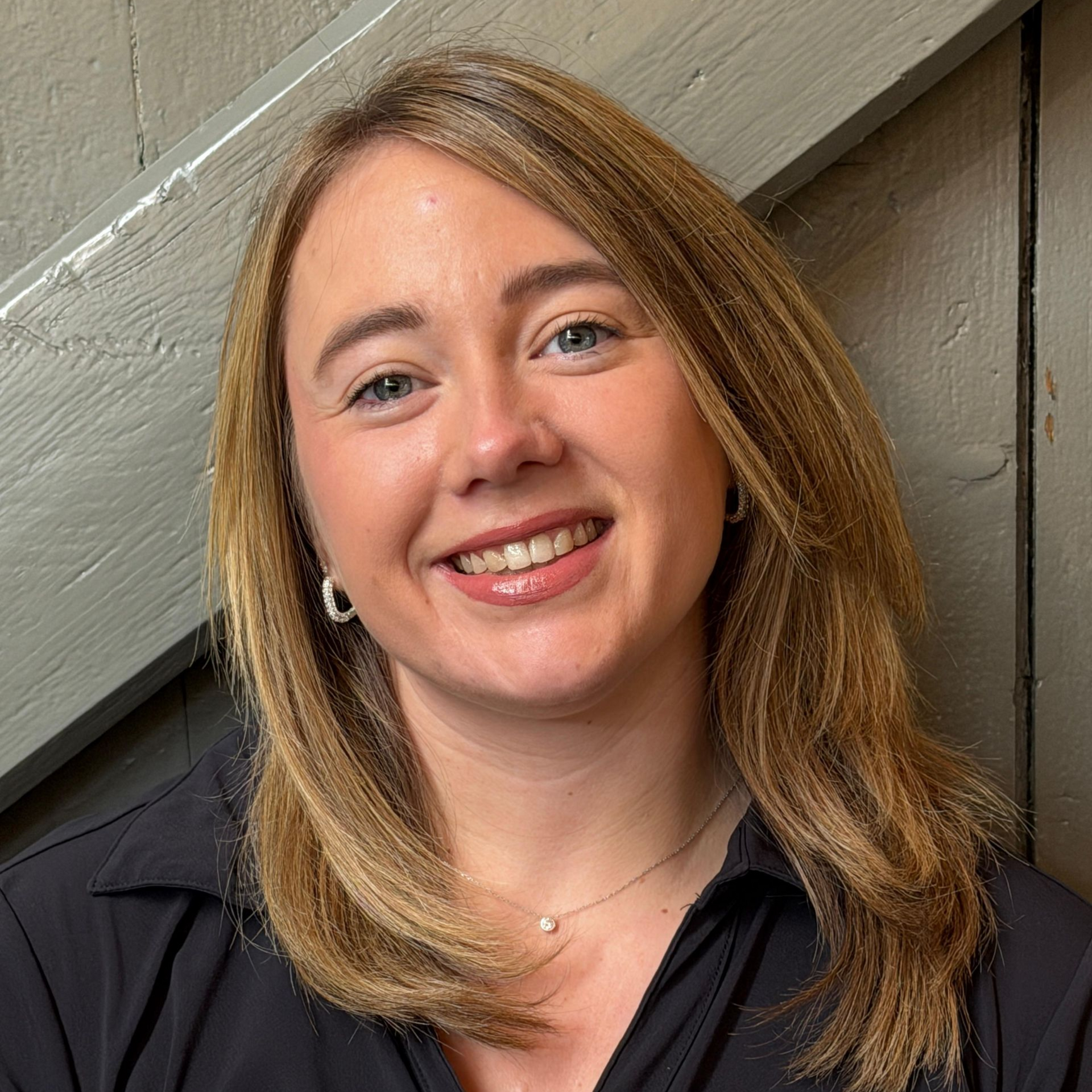 Een vrouw lacht voor een houten muur