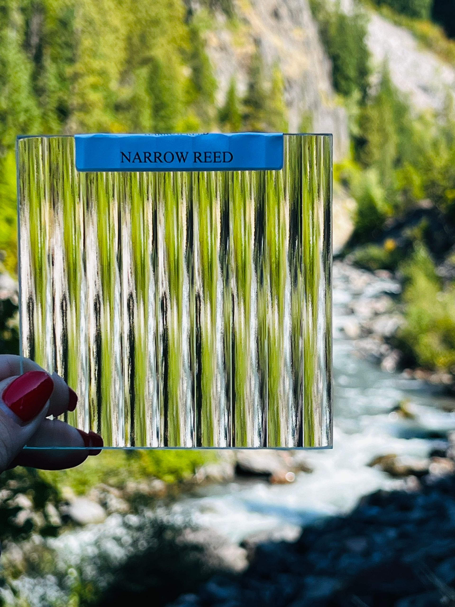 A person is holding a piece of glass that says narrow reed