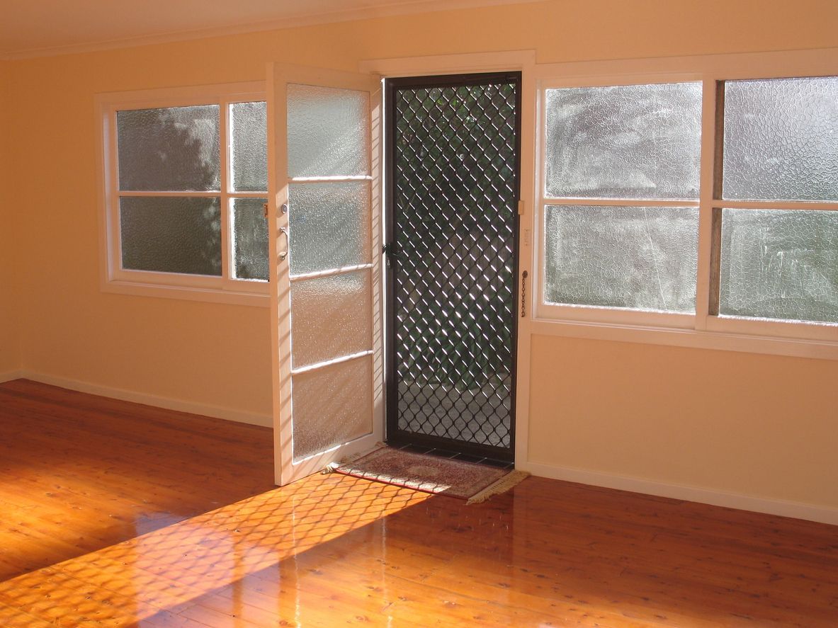 An empty room with a sliding glass door and lots of windows.