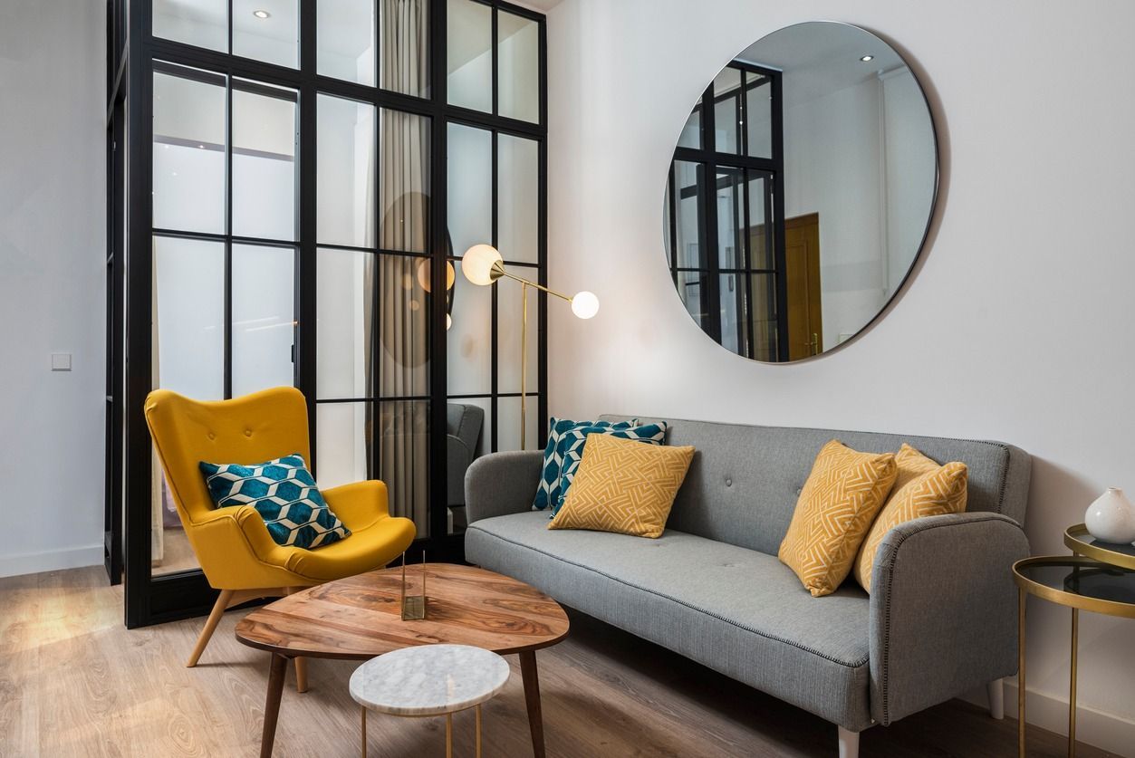 A living room with a couch , chair , table and mirror.