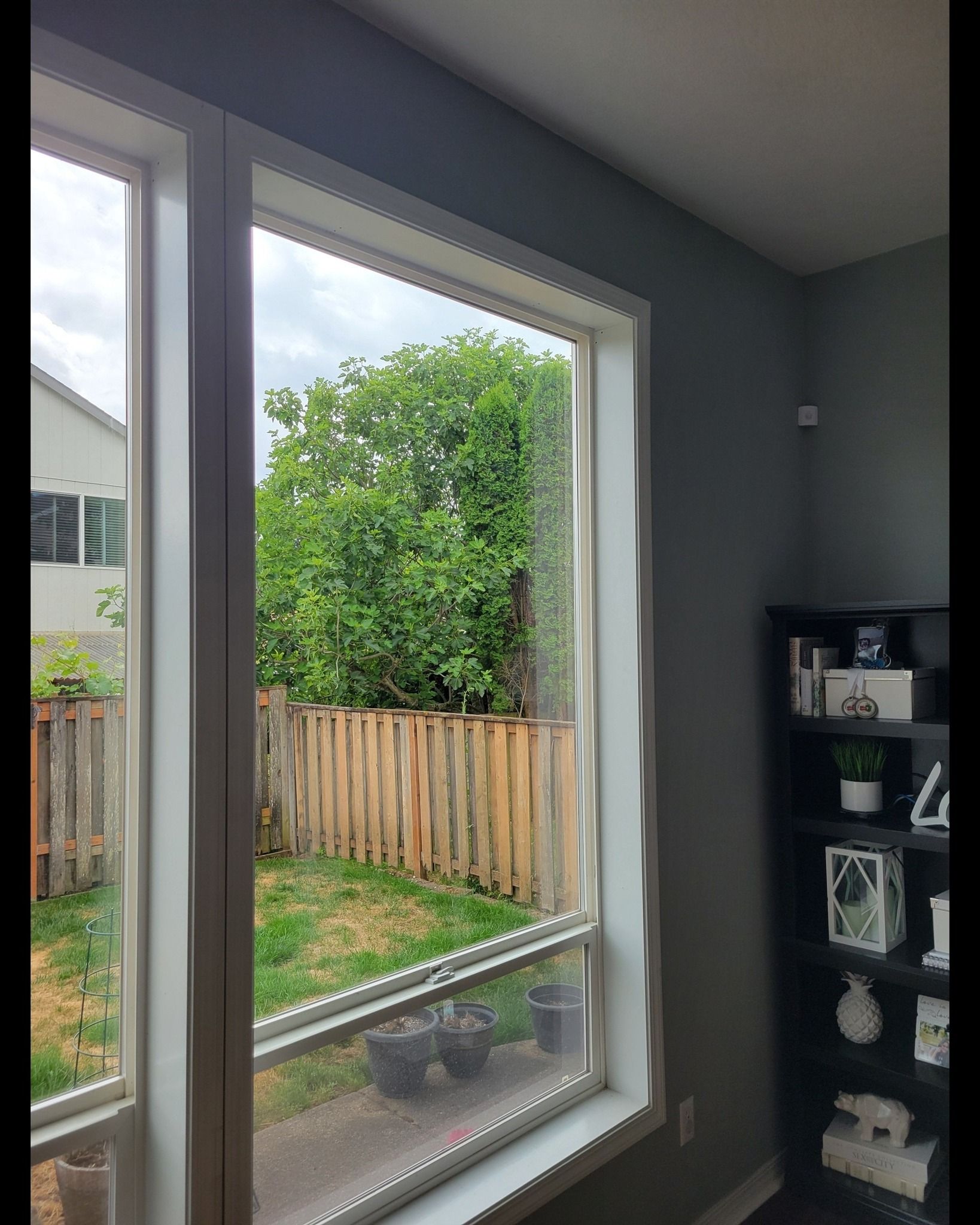 A living room with a large window and a fence in the background.