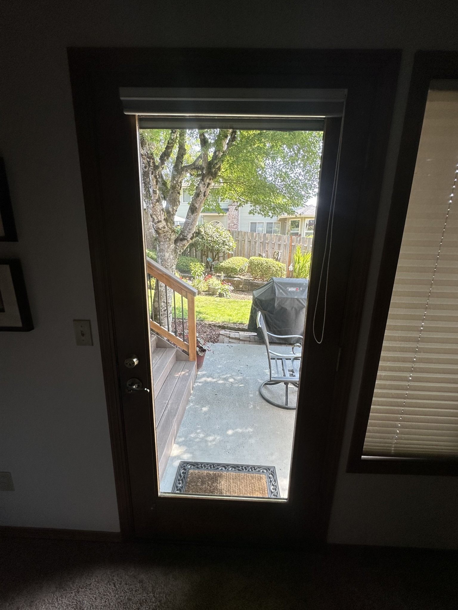 A sliding glass door leading to a patio with a grill and chairs.