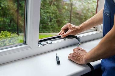 A man is installing a window seal on a window sill.