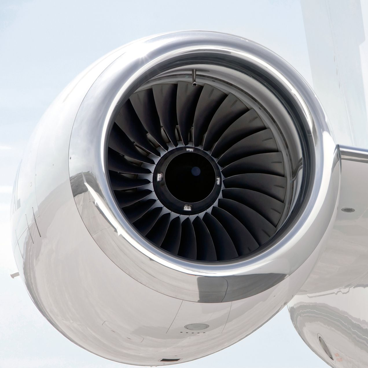 Airplane wing and engine viewed through a window, above a sea of clouds.