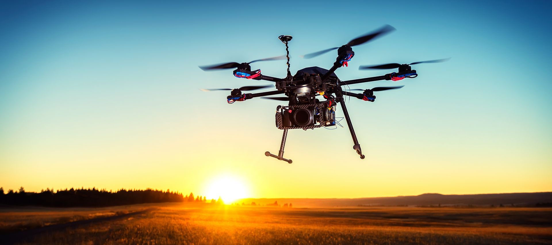 Drone flying at sunset over a field.