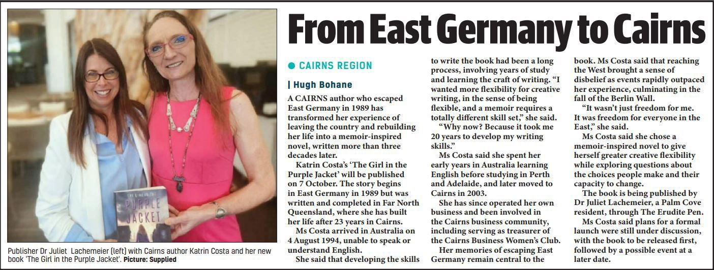 Two women pose beside a newspaper article titled “From East Germany to Cairns”