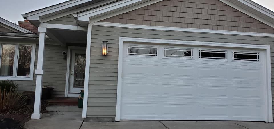 A house exterior with a white garage door and a front door under a small porch.