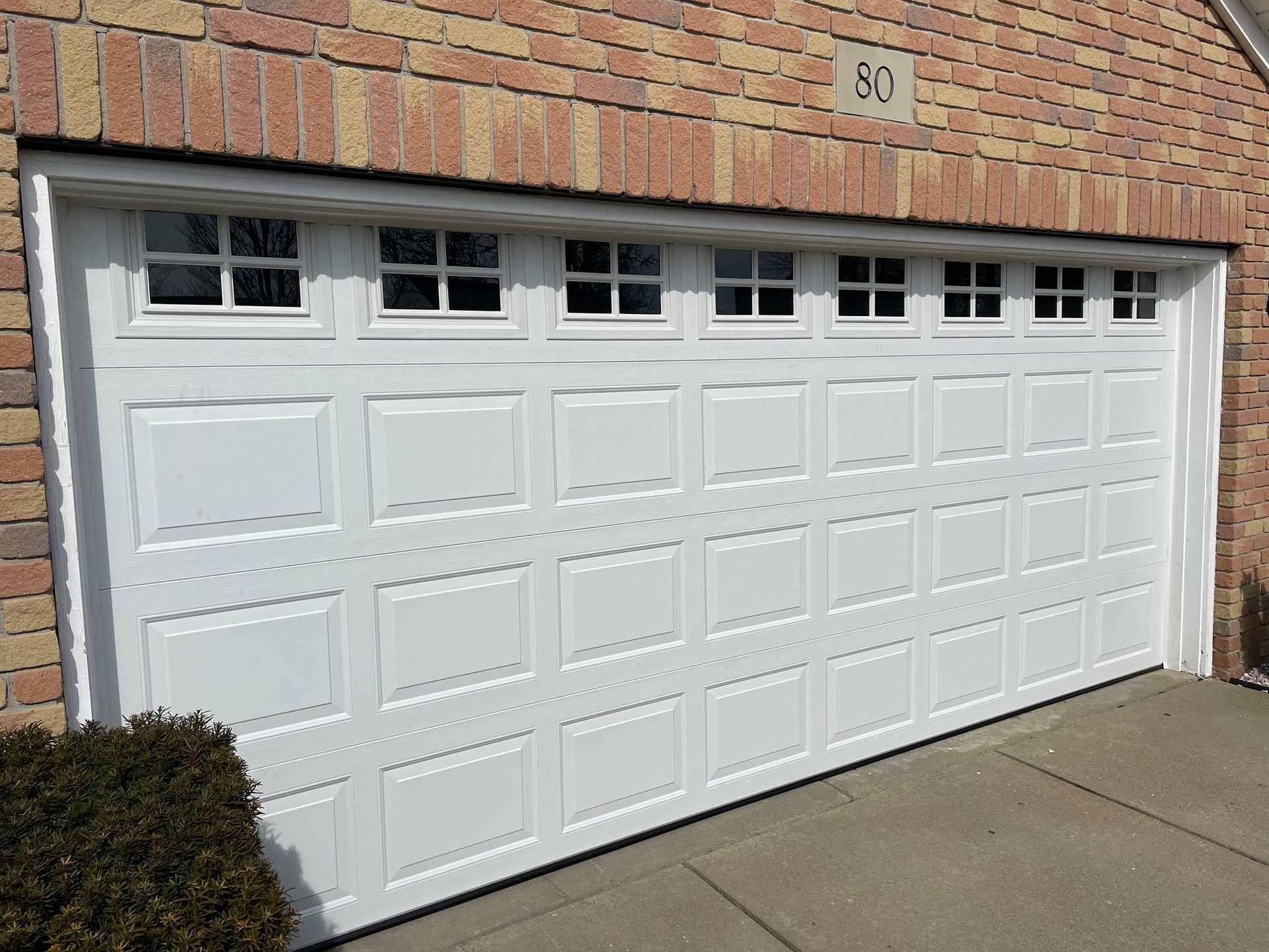 White garage door with small windows, set in a brick building.