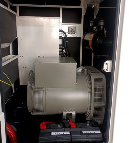 Generador industrial gris y baterías dentro de un compartimento de maquinaria