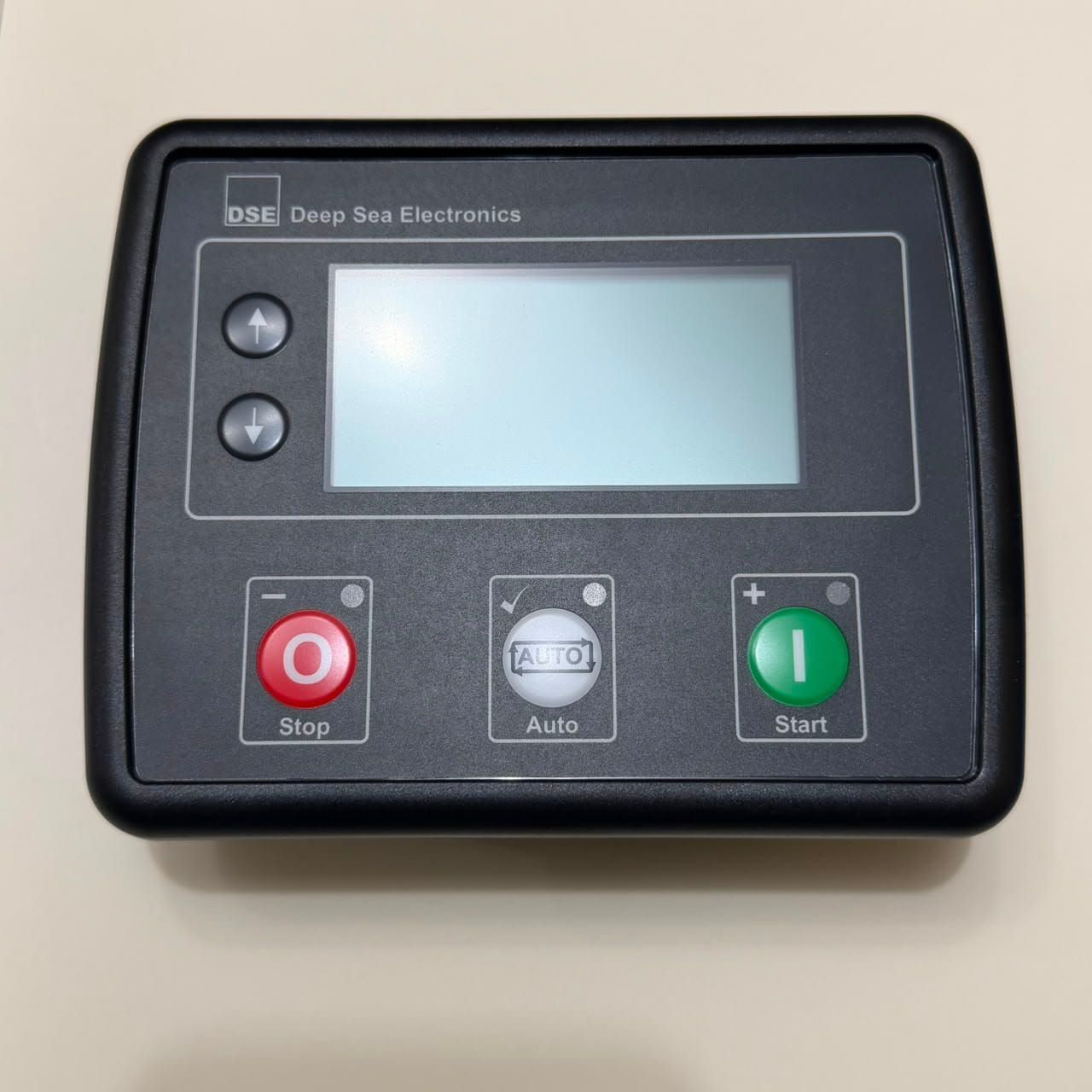 Panel de control con pantalla y botones de parada (rojo), automático (gris) y arranque (verde) en una caja negra.