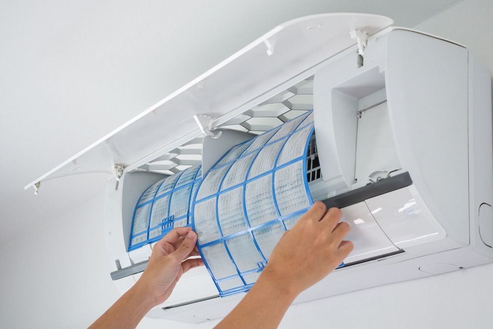 A Person is Cleaning the Filter of an Air Conditioner — Cool Tropics Air Conditioning & Refrigeration in Mission Beach, QLD