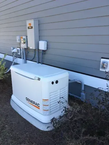 A generator on wheels sits on a brick surface next to wooden planks.