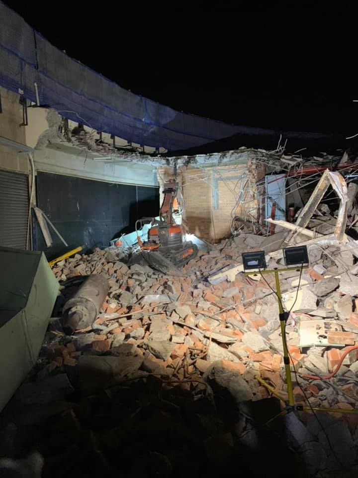 A brick building is being demolished at night with a bulldozer — Newcastle Cut & Drill In Boolaroo, NSW