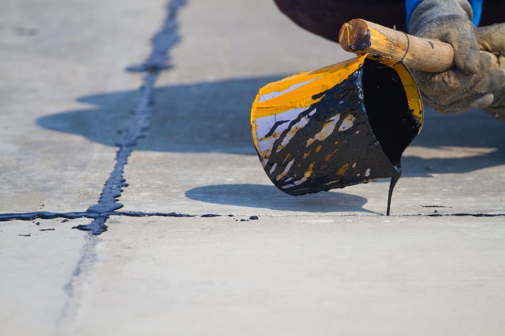 A Person Is Pouring Liquid From A Bucket Onto A Concrete Surface — Newcastle Cut & Drill In Boolaroo, NSW