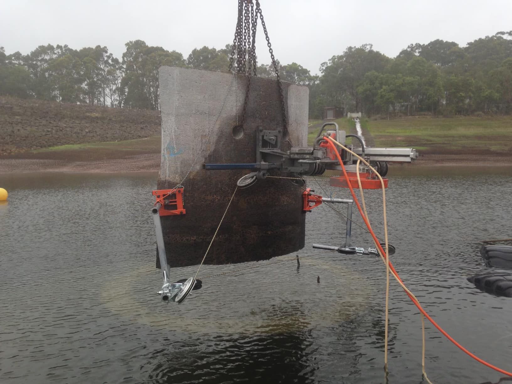 A large piece of concrete is being lifted into the water by a crane — Newcastle Cut & Drill In Boolaroo, NSW