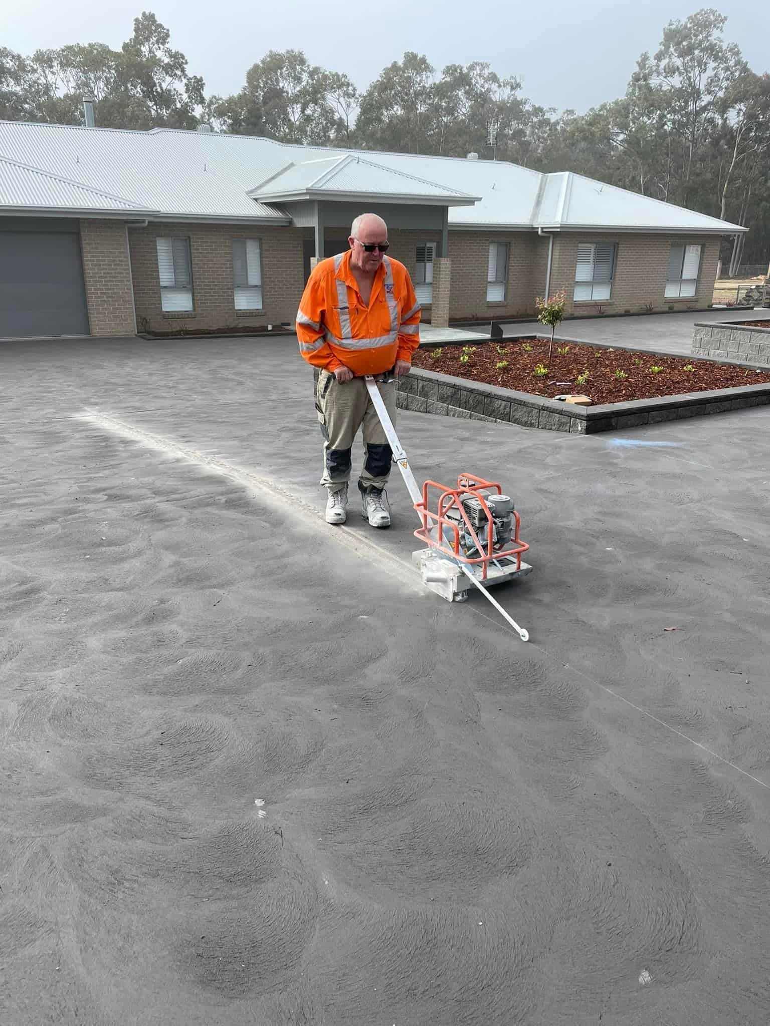 A man is painting a line on the road in front of a house — Newcastle Cut & Drill In Boolaroo, NSW